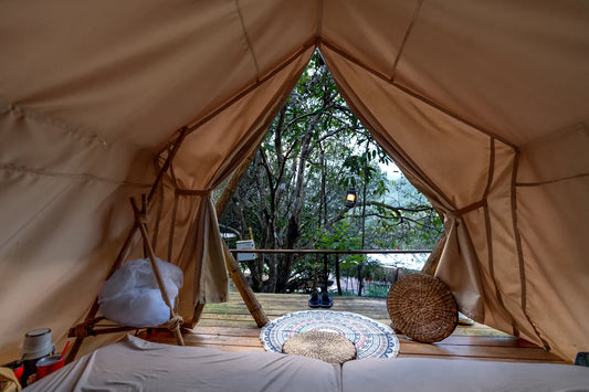 Ruhiges Zeltinneres mit gemütlichem Bett am Waldrand, Symbolbild für die Pflege von Naturmaterial Schlafsäcken beim Camping