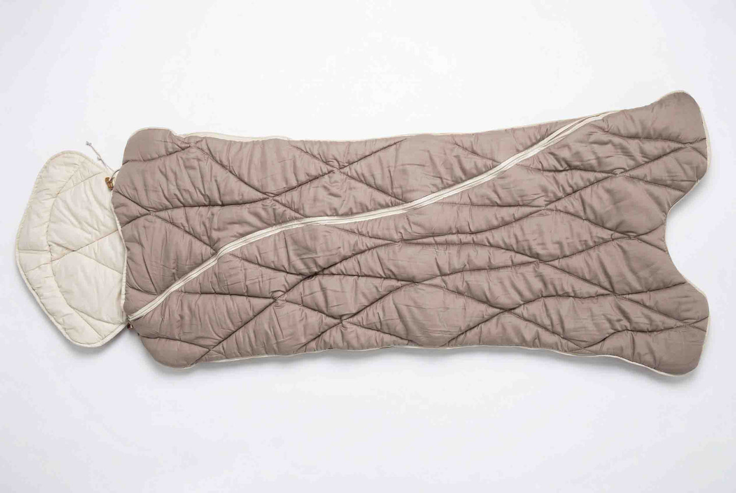 Der Origobag Premium Kamelhaar-Schlafsack aus nachhaltigen Naturmaterialien verfügt über eine taupefarbene, gesteppte Außenseite und ein weißes Innenfutter. Hier ist er offen und flach ausgebreitet zu sehen; er verfügt über einen Kapuzenbereich für zusätzlichen Komfort.